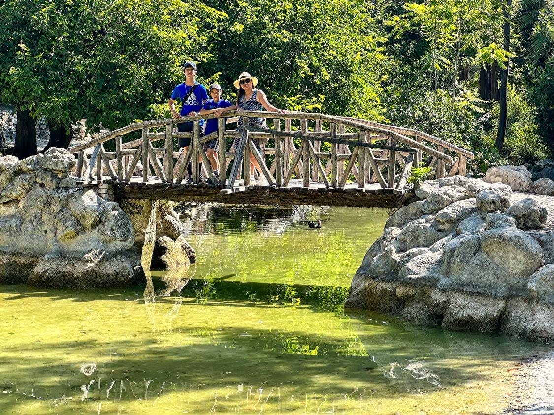 A family walks across a pretty bridge in the Greek National Gardens in Athens