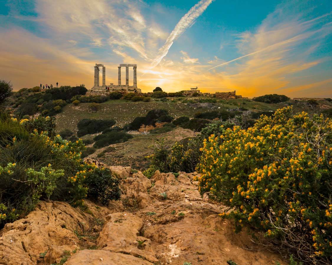 Sunset over a cliffside Temple of Poseidon in Sounion, Greece