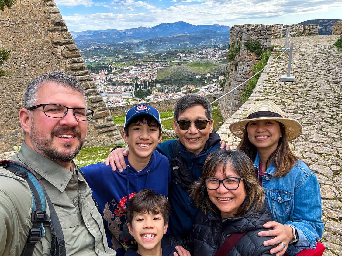 A mixed race travel family smiles for a selfie at Palamidi Fortress in Nafplio, Greece