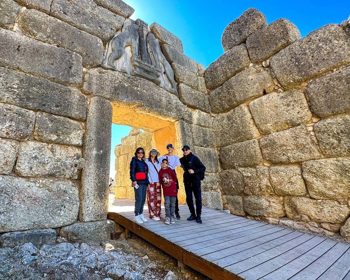 A multi-generational travel family stand beneath the Lion Gate in Mycenae