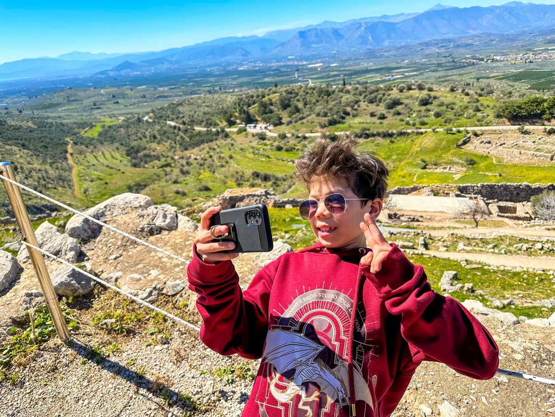 A young boy takes a selfie at an overlook in the Mycenae Palatial Complex