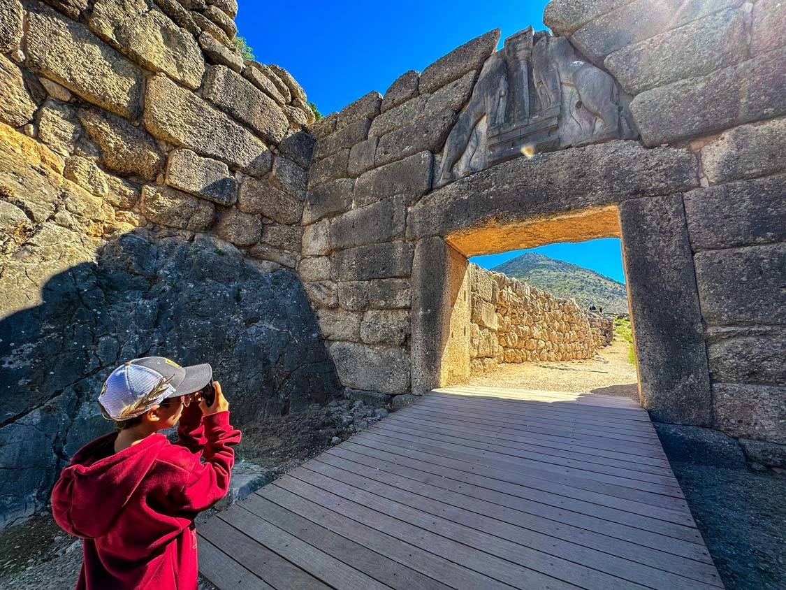 A young boy takes a photo of the Lion Gate in Mycenae