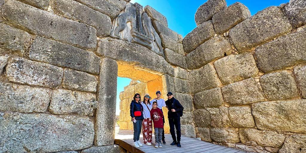 A multi-generational travel family poses in front of the Mycenae Lion Gate in Greece