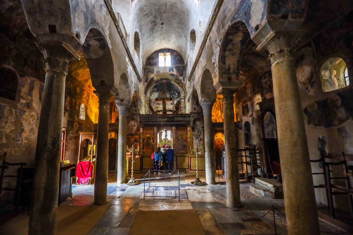 A family walks among the frescoes of an ancient church in Mystras, Greece