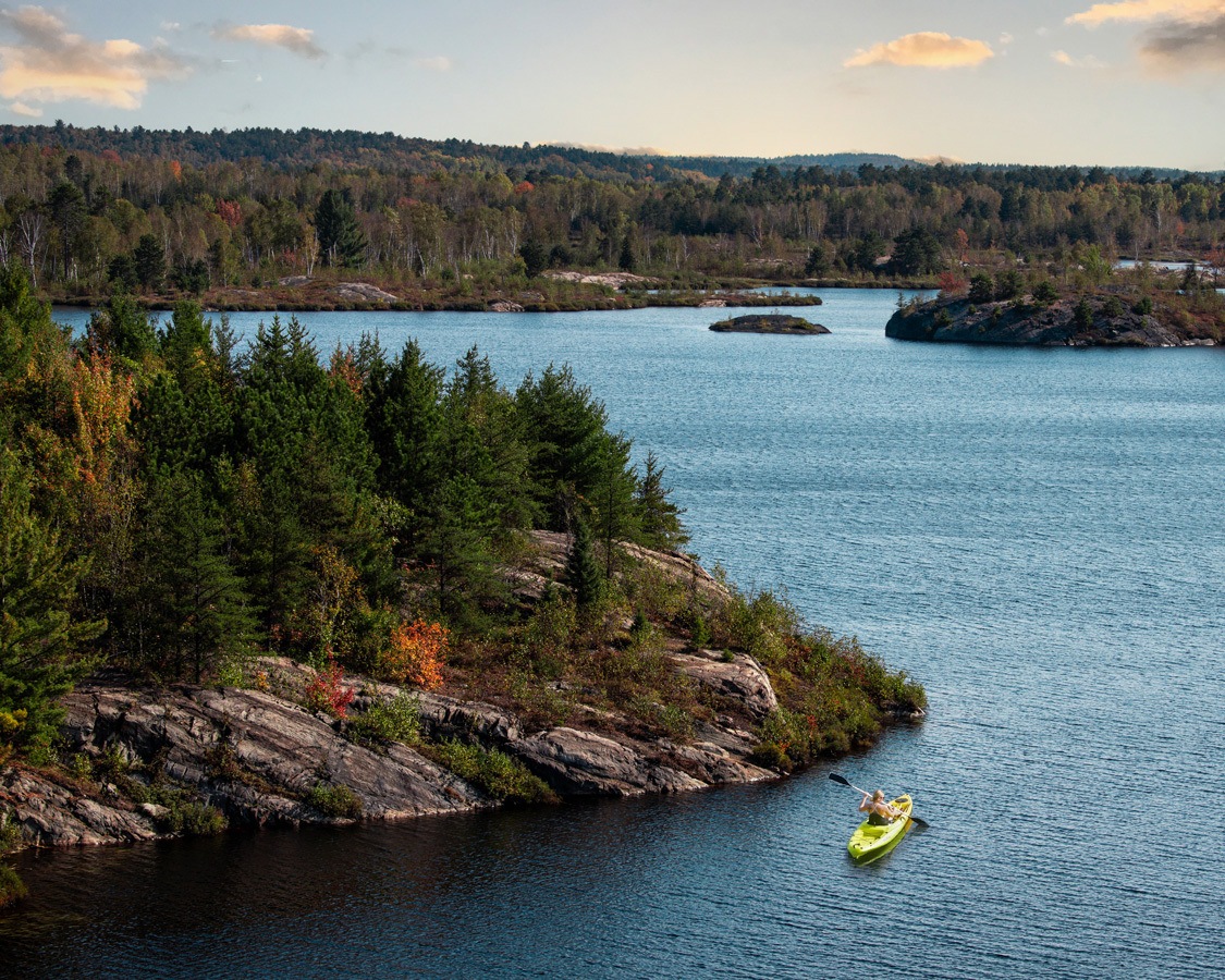 A woman kayaks amongst the fall scenery in Lake Laurentian Conservation Area