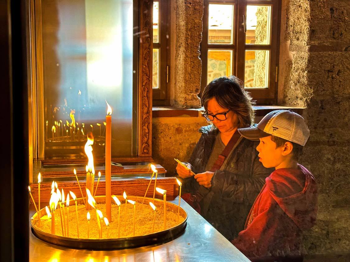 A young boy and his grandmother light a candle at the Grand Meteoron Monastery