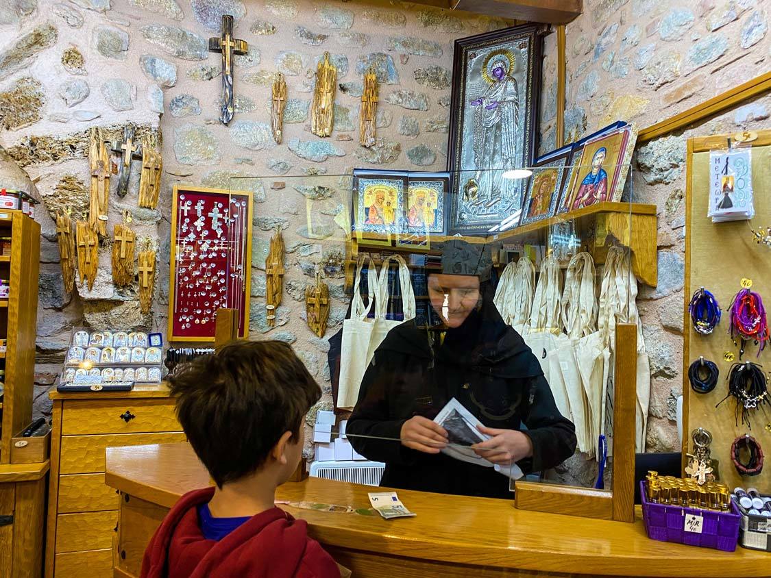 A young boy purchases a souvenir from a nun in Meteora, Greece