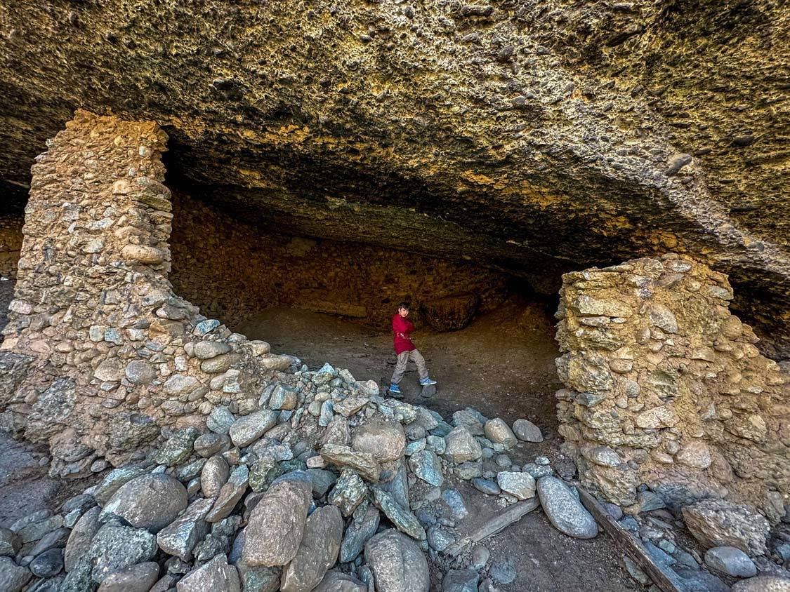 A boy walks through a hermit cave in Meteora Greece