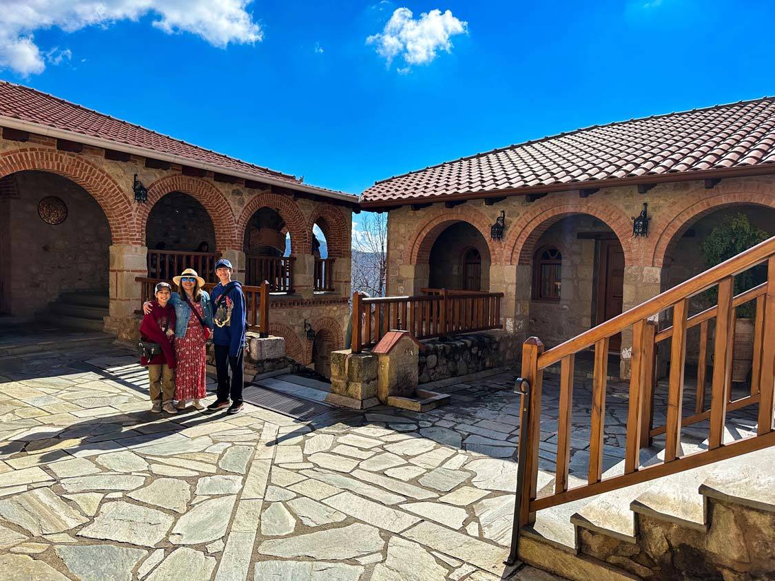 A woman and her two sons pose for a photo in the courtyard of the Monastery of the Grand Meteoron