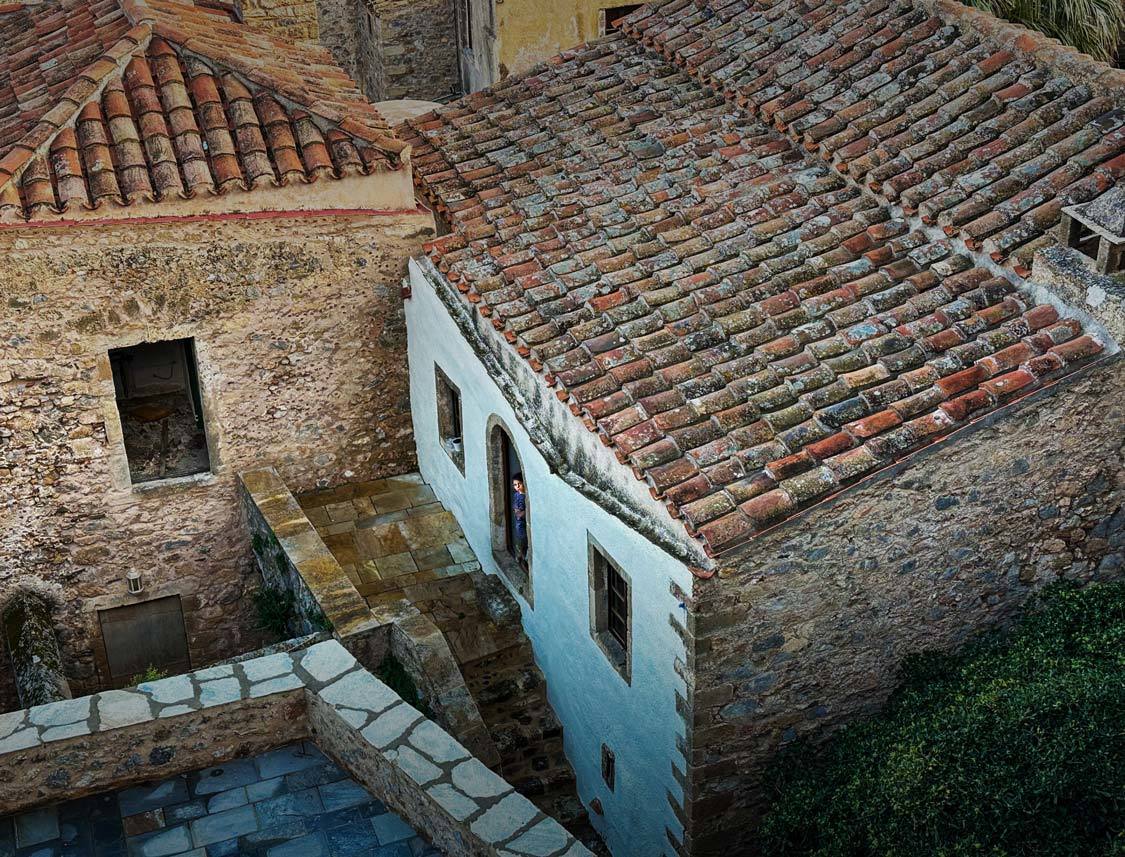 A girl looks out from a house in one of Monemvasia's historic houses