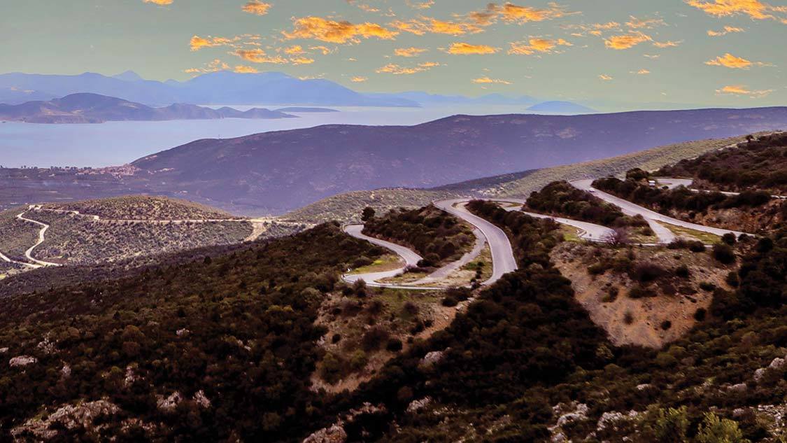 Winding roads at sunset over the Aegean Sea on a Greek road trip