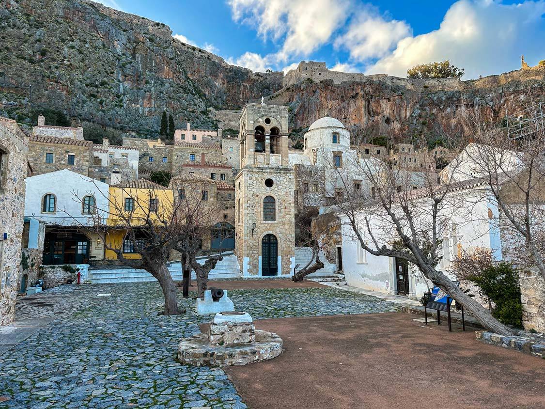 Looking up at the Monemvasia Acropolis from a tree-filled courtyard