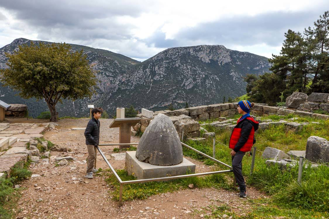 Two boys look at the Navel of the World monument in Delphi, Greece