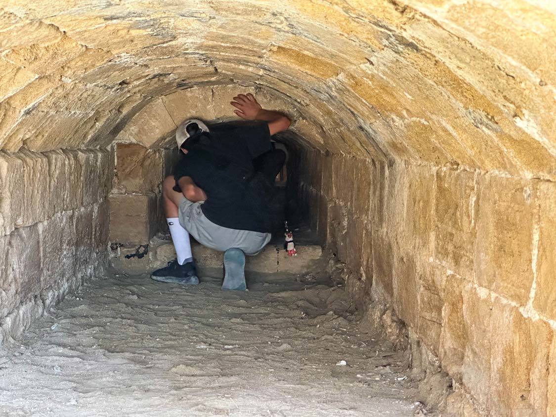 Two boys crawl through a tunnel in the Rocca a Mare to see the museum inside