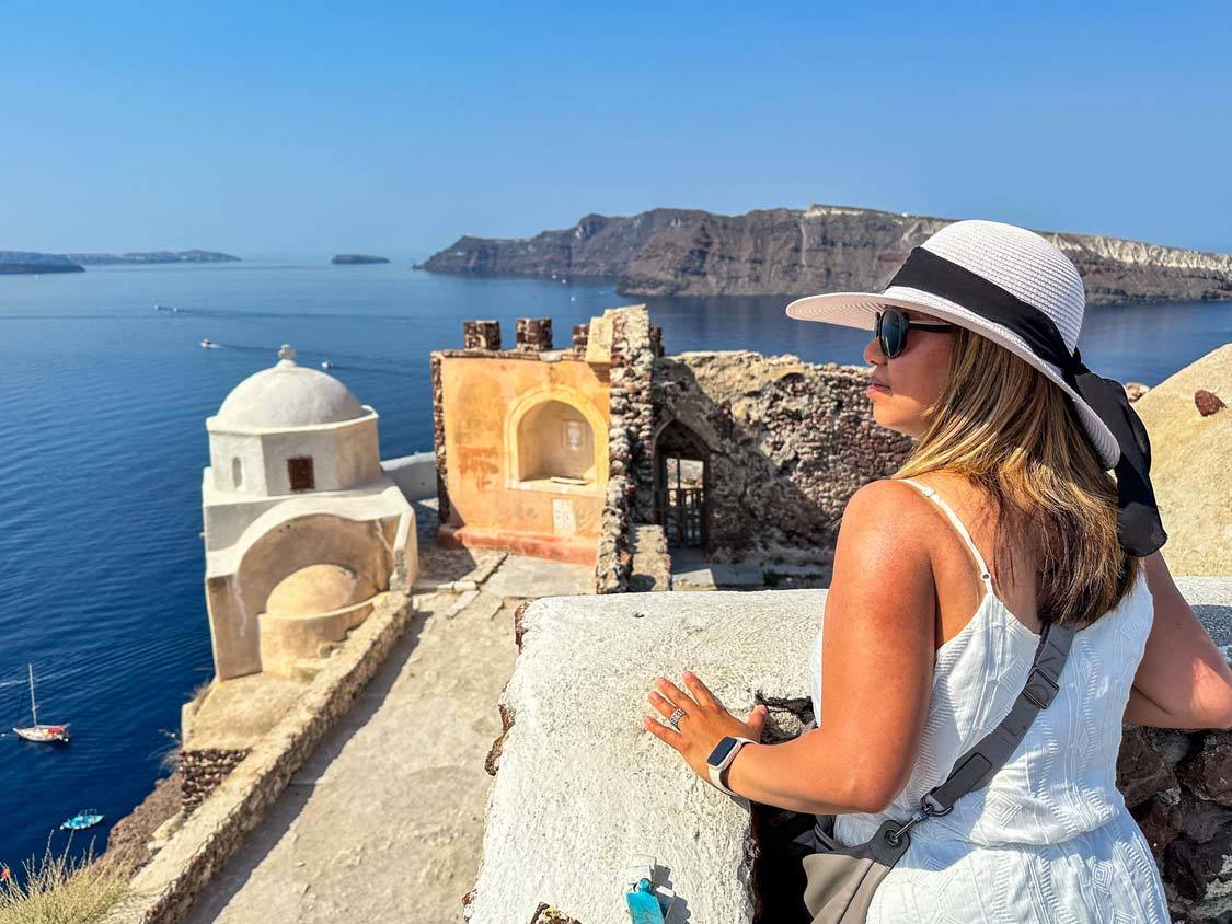 An asian woman looks out over the Oia Castle in Santorini