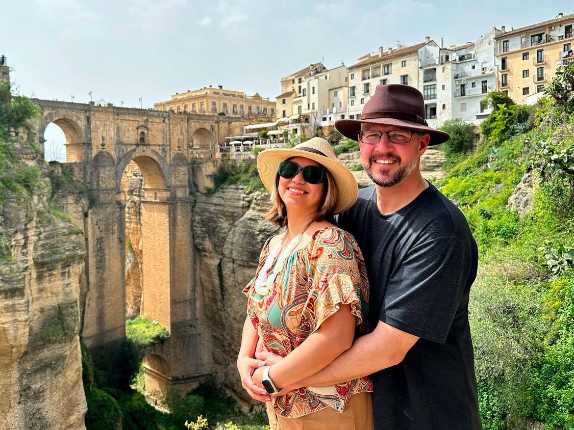 A man and his wife pose for a photo in front of the Ronda Aqueduct in Spain