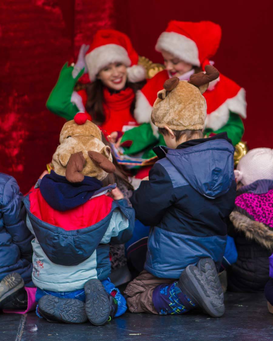 Two young boys in reindeer hats listen to elves tell stories at the Distillery District Winter Village