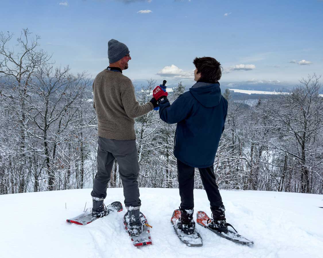 A father and his son share a drink while snowshoeing at Kenauk Adventures in Montebello, Quebec