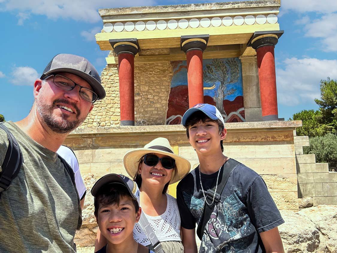 The Wandering Wagars family smiles at the camera in front of a reconstructed ruin in the Palace of Knossos