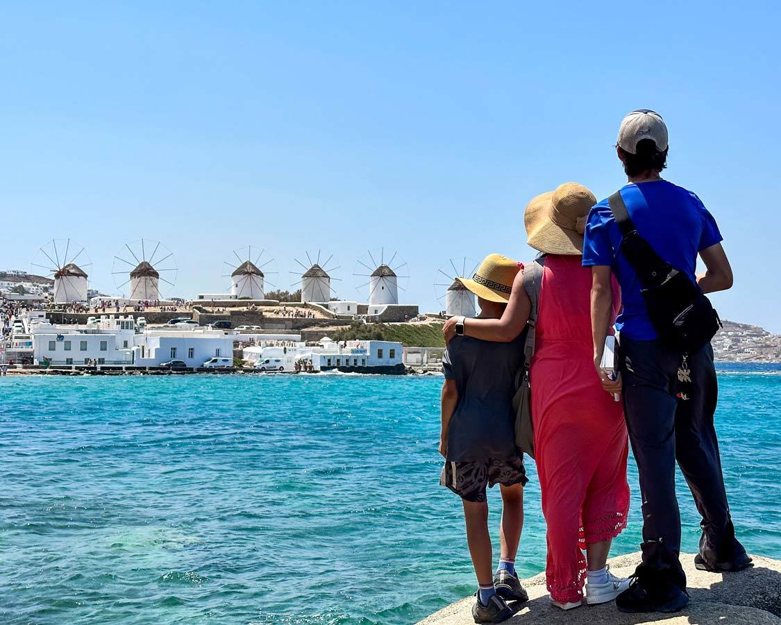 A mother and her two children look out over the Aegean Sea at the Mykonos Windmills