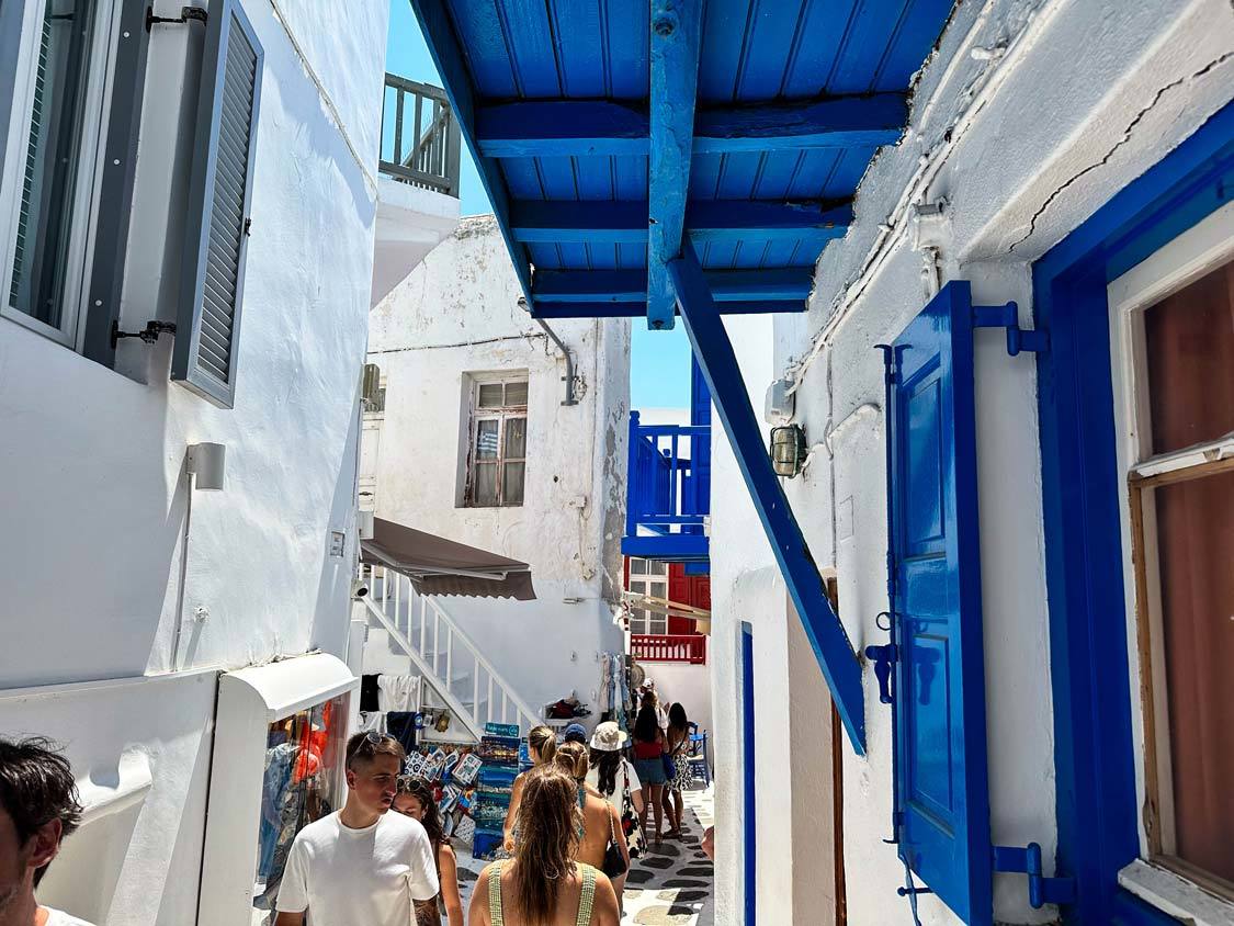 Crowds push through narrow lanes amidst whitewashed buildings in Little Venice, Mykonos