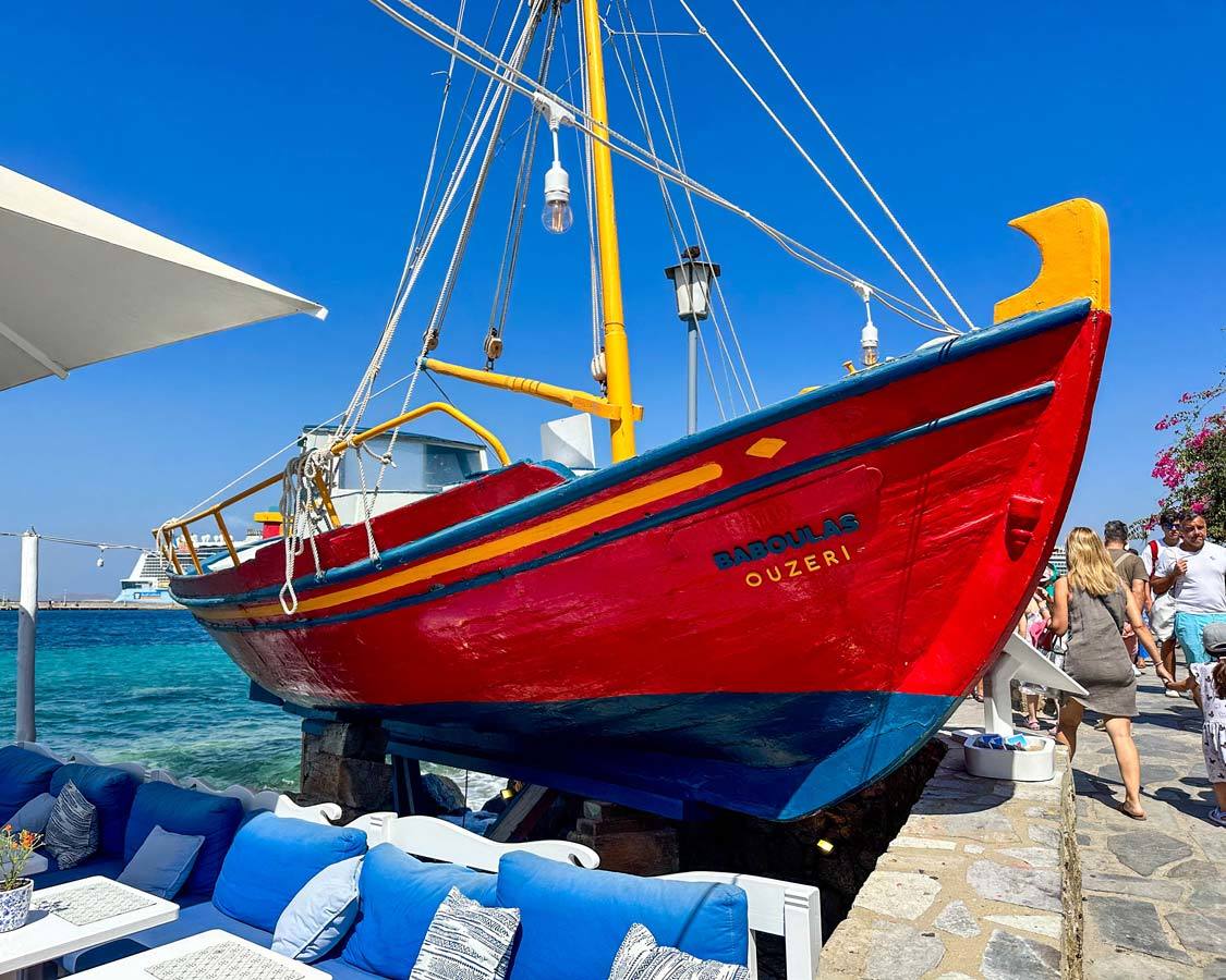 A drydocked fishing boat painted in bright red and blue near the Chora Harbor in Mykonos