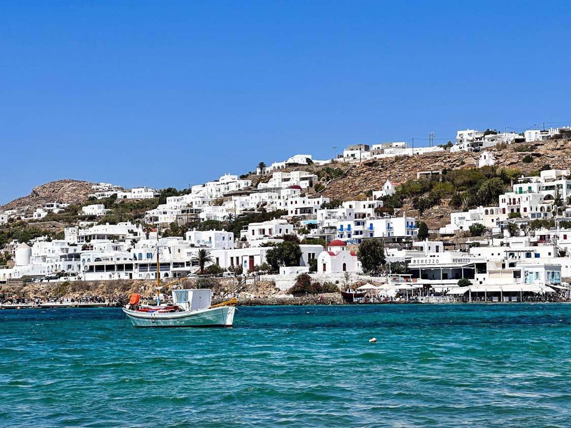 A fishing boat and hillside houses in Mykonos, Greece