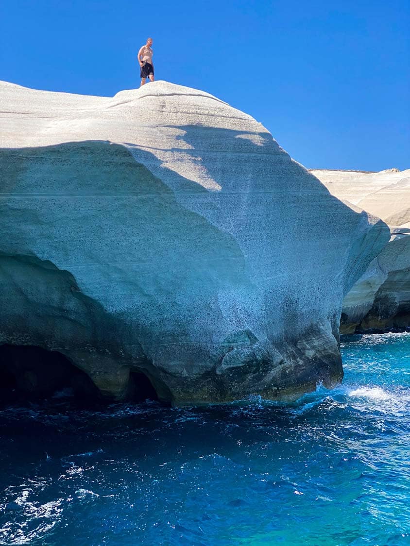 A man prepares to jump from a rock arch on Sarakiniko Beach on Milos, Greece