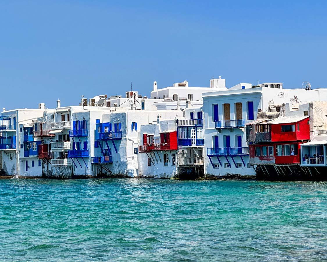 Rows of whitewashed buildings with colorful windows and doors at Little Venice in Chora. Mykonos