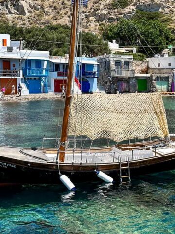 A rustic fishing boat bobs in the waters of Klima on the island of Milos