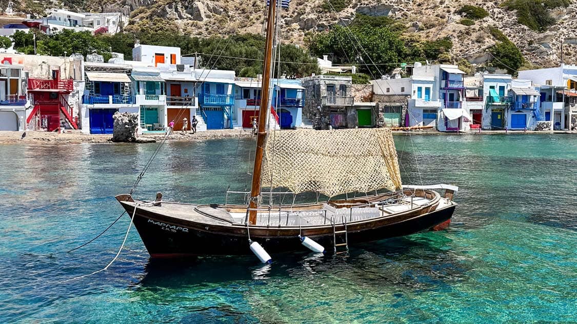 A rustic fishing boat bobs in the waters of Klima on the island of Milos