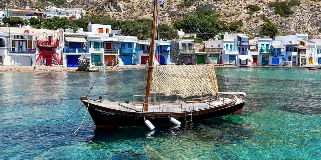 A rustic fishing boat bobs in the waters of Klima on the island of Milos