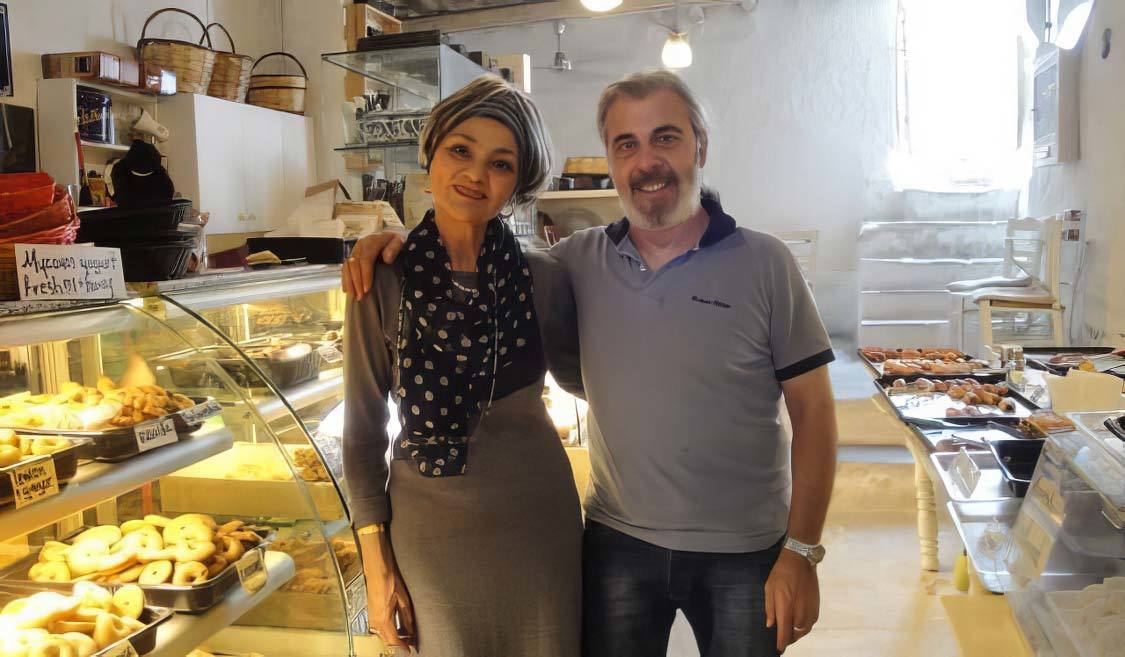 A man and women, the owners of Gioras Bakery on Mykonos pose in their historic shop