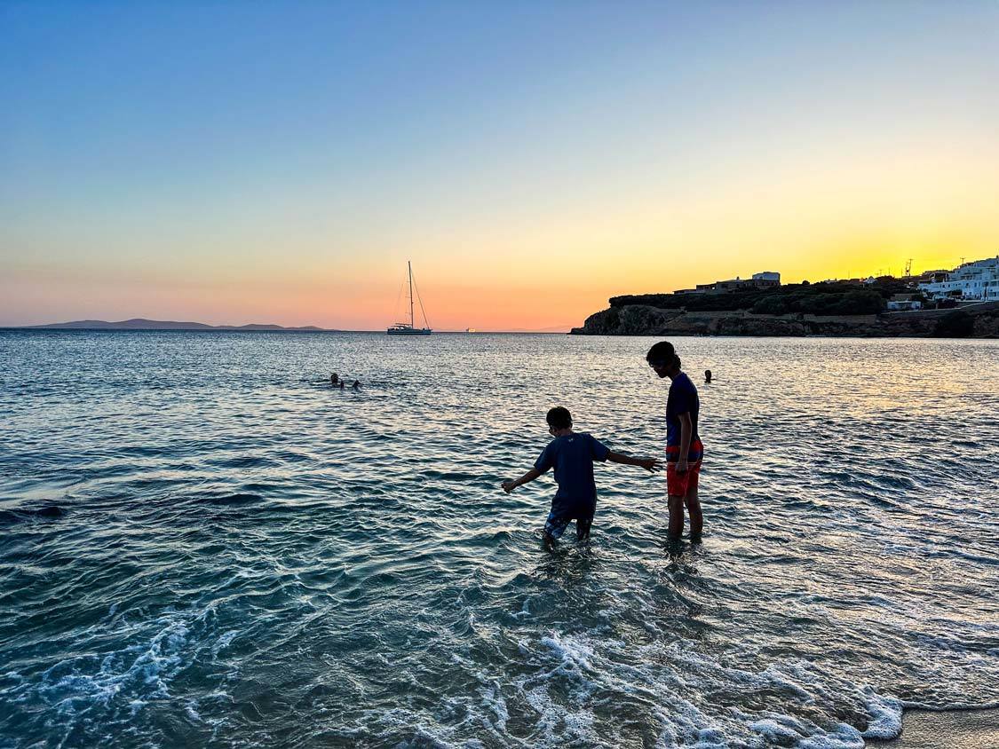 Two boys swim at sunset on Agio Stephanos Beach on Mykonos Island