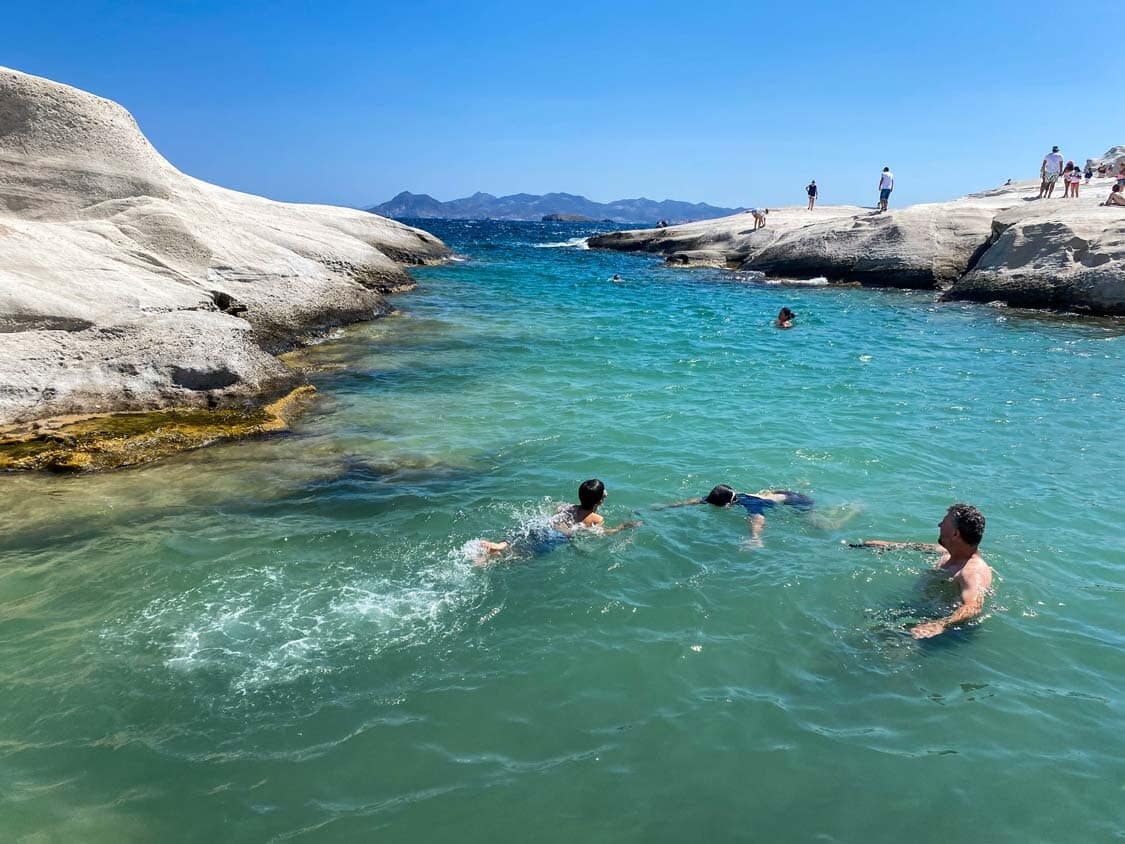 A family swims in a sheltered bay at Sarakiniko Beach