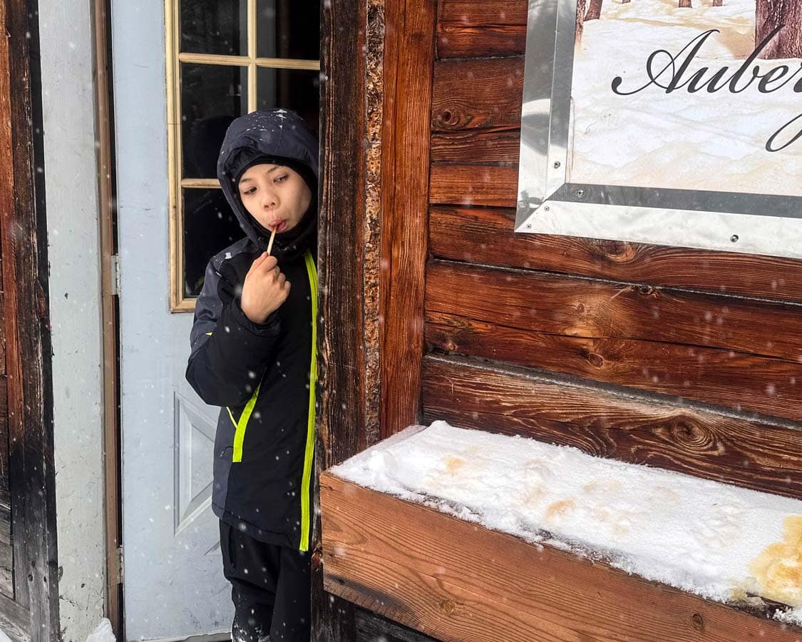 A young boy eats maple taffy at a sugar shack in Quebec