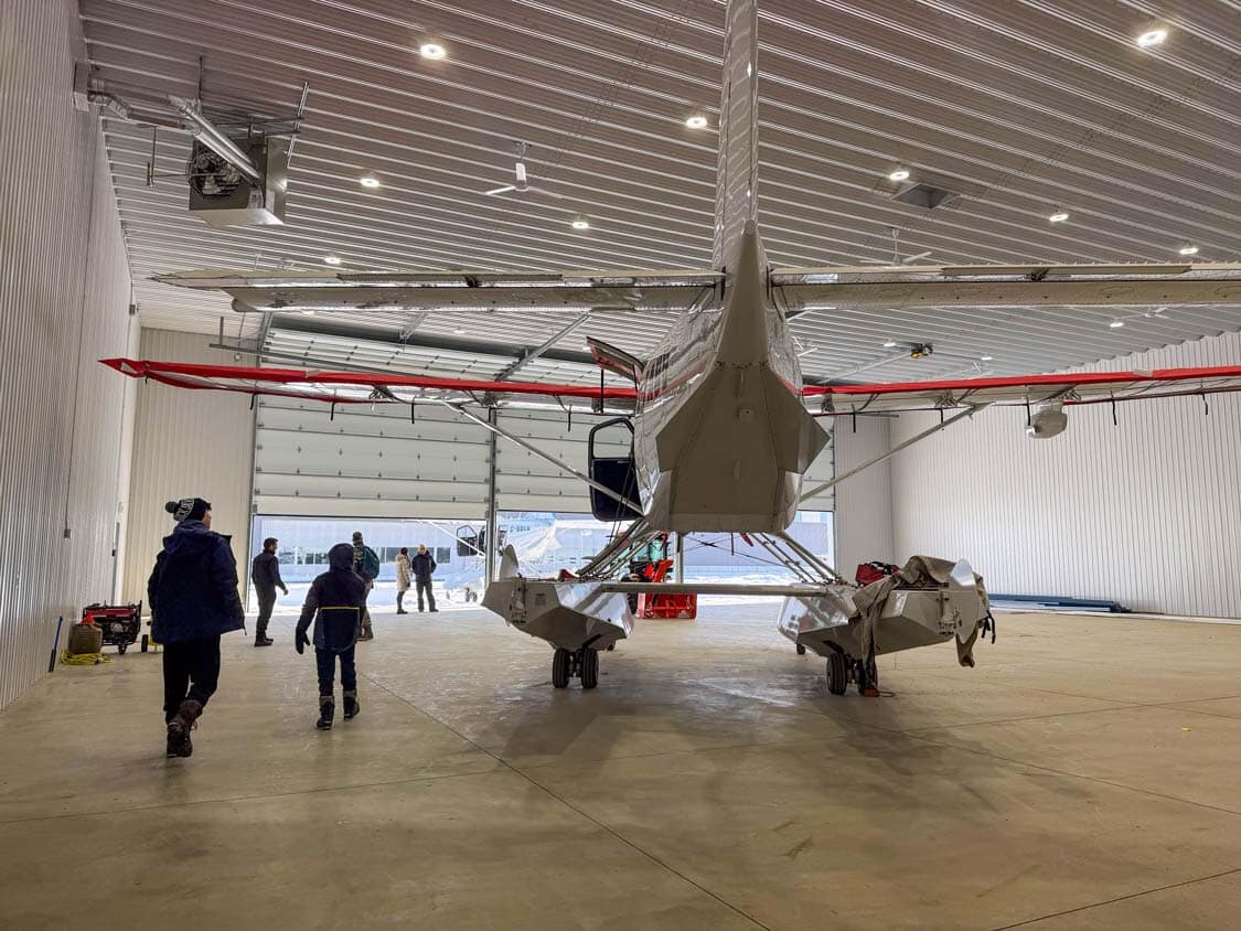 Two boys walk next to a floatplane in a hangar at the Trois-Rivieres Airport