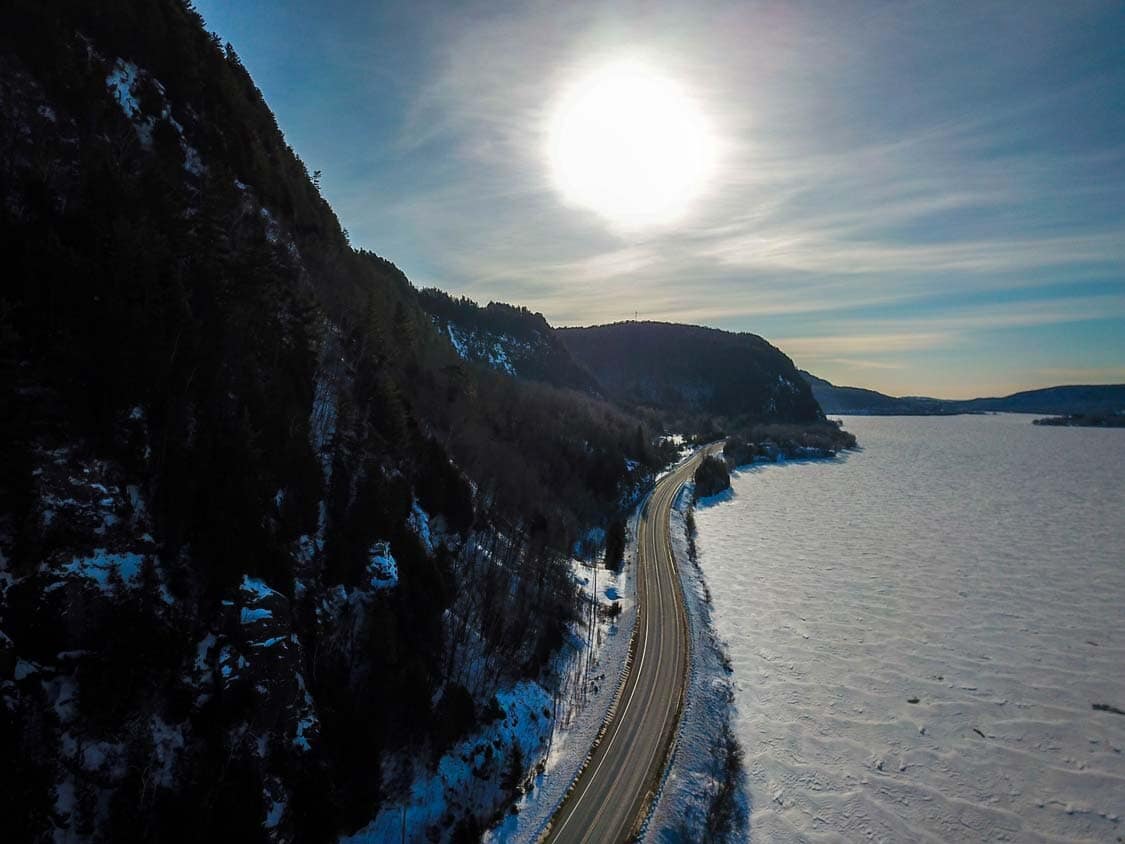 Towering cliffs line a highway next to the frozen Saint Maurice River