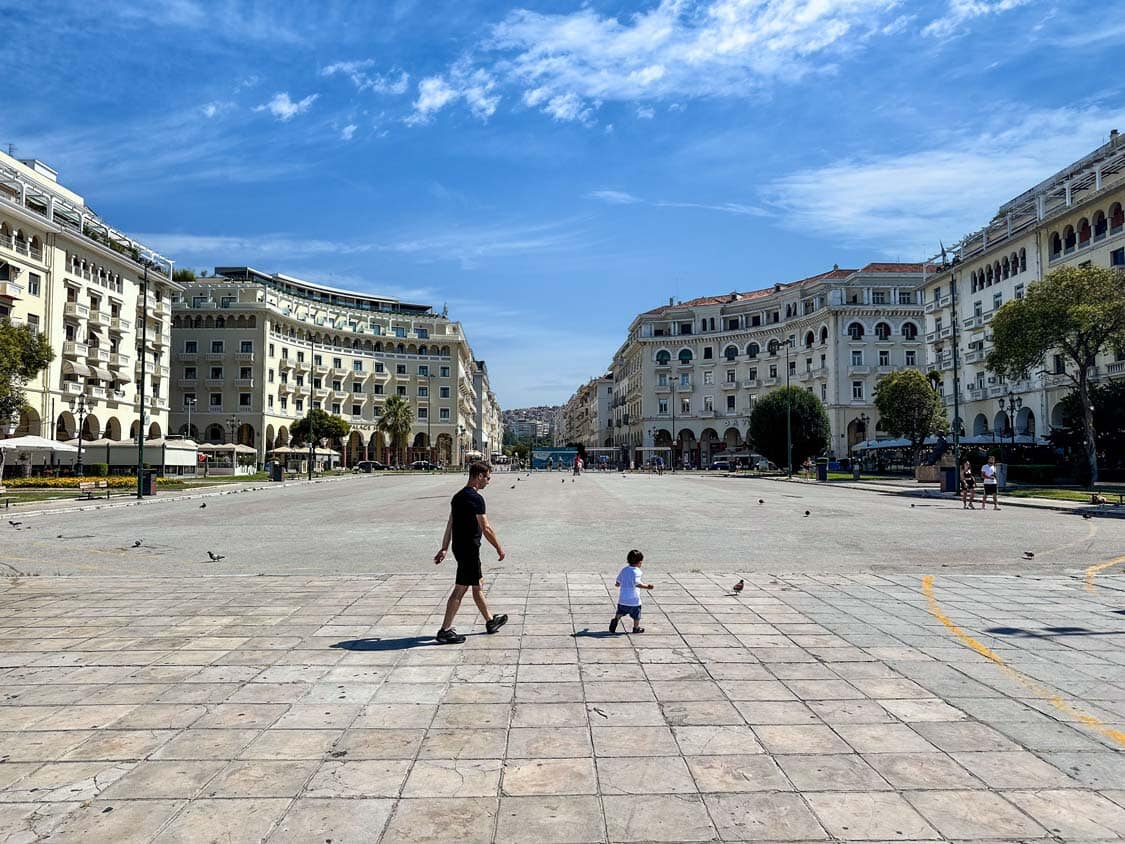 A father walks with his young son through the wide Parisian-style boulevards of the Thessaloniki waterfront