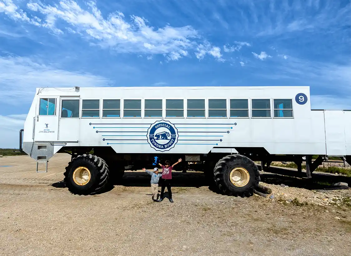 Two boys pose in front of a huge truck called a Tundra Buggy in Churchill, Manitoba