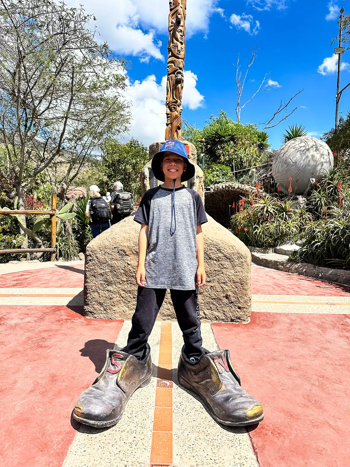 A young boy poses with funny shoes on both sides of the ecuator