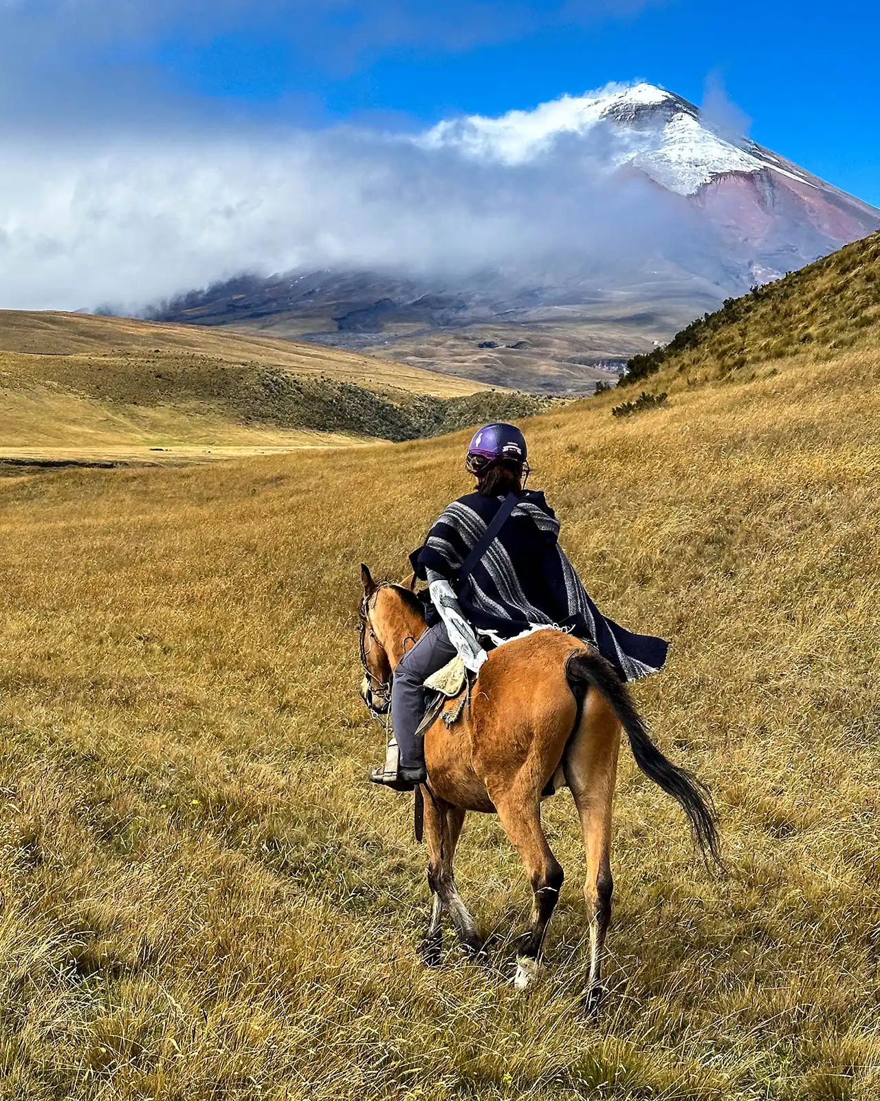 A woman rides a horse through Cotopaxi National Park