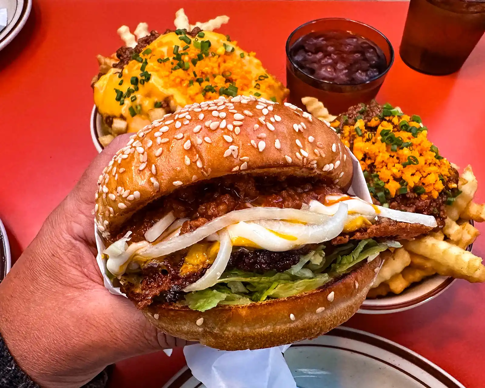 a hand holds a hamburger and loaded fries from Class Clown Hamburgers in downtown Calgary