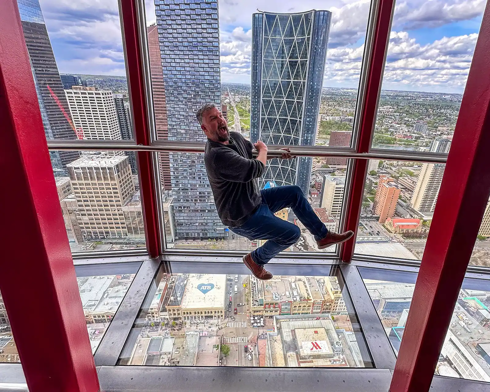 Kevin Wagar goofs off pretending to fall off of the Calgary Tower
