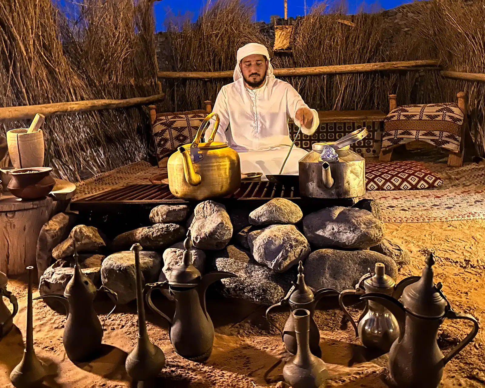 A man dressed in Bedouin garb brews coffee at the Platinum Heritage desert camp