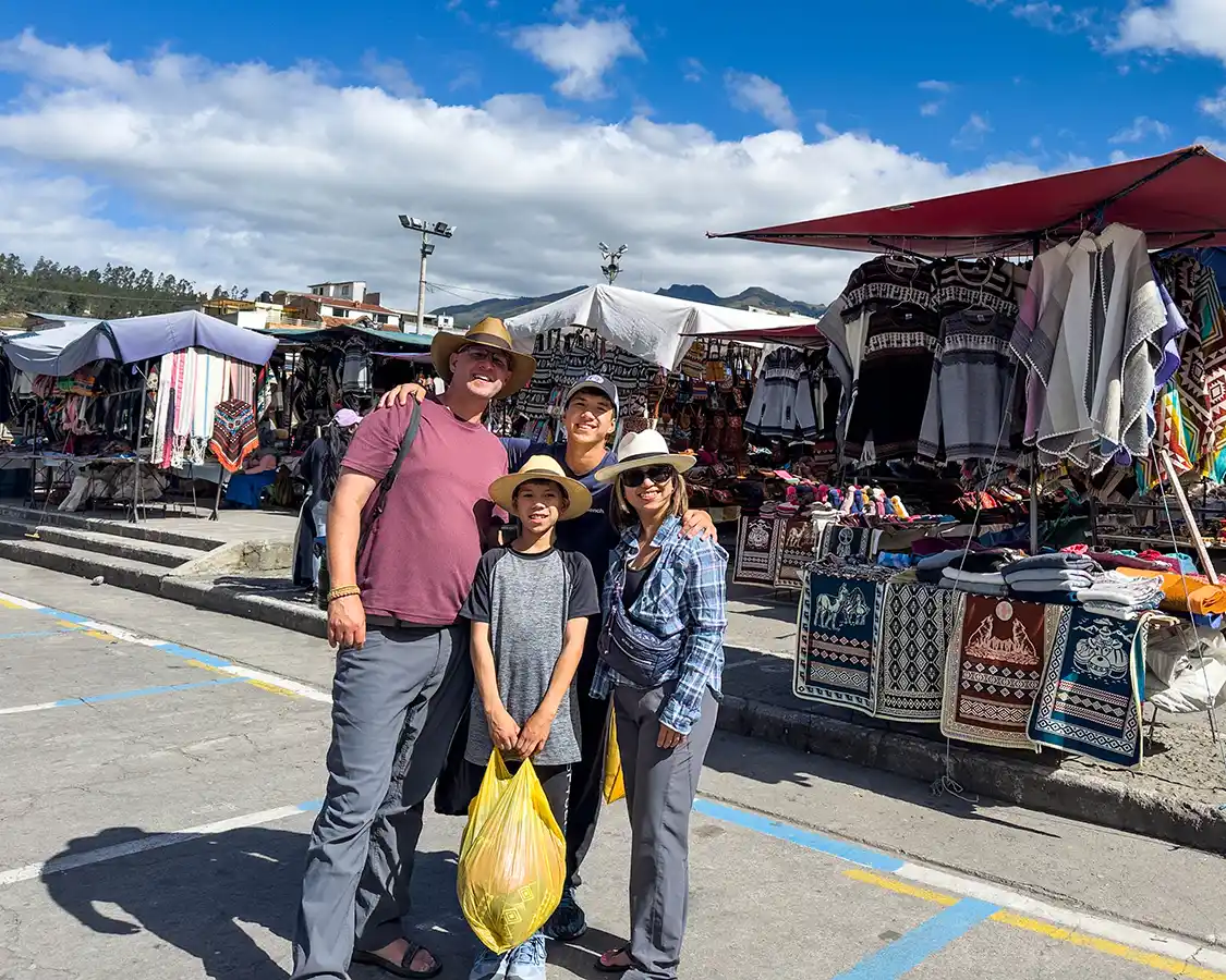 A family smiles together while shopping at the Otavalo Textile Market