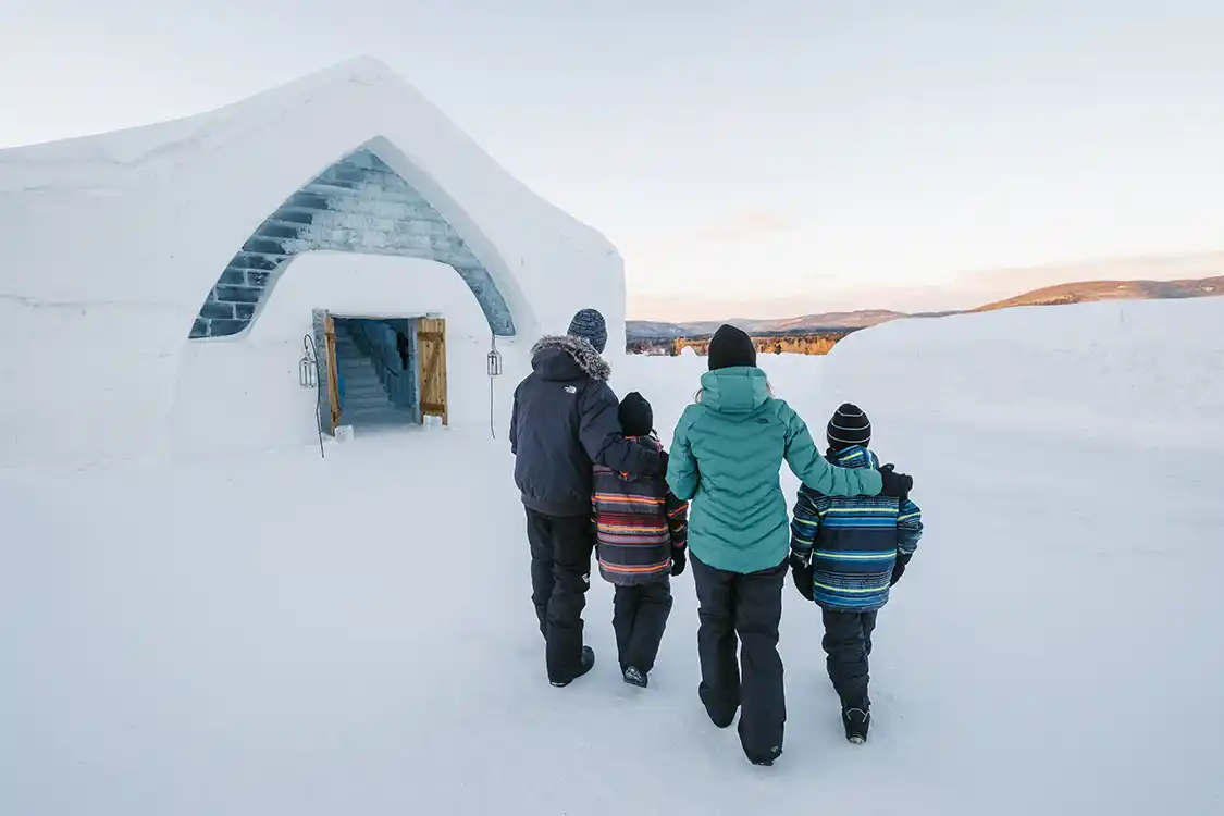 A family walks toward a hotel made of ice in Valcartier Quebec