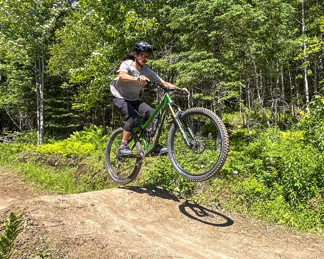 A man in cycling gear hits a jump at Empire47 Mountain Bike trail near Quebec City