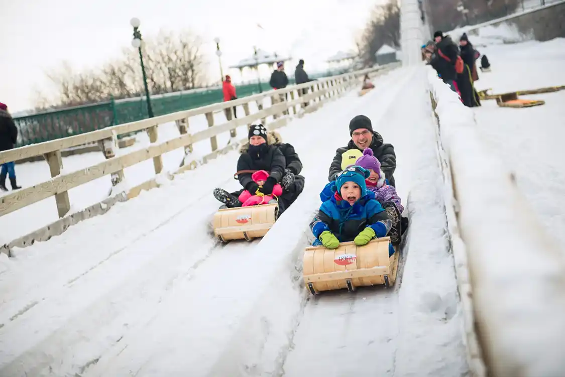 A family laughs while sliding down a man-made toboggan hill in Quebec City