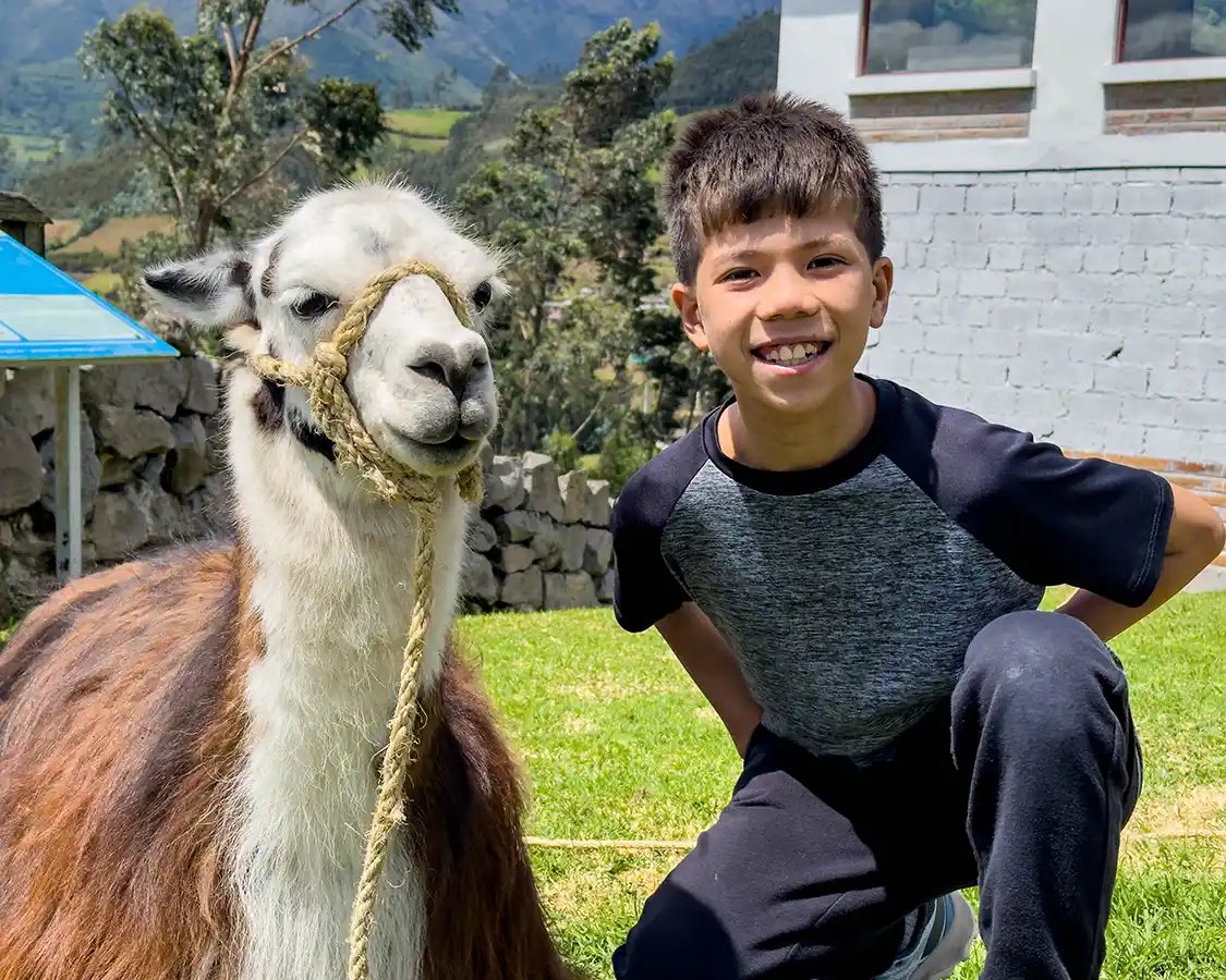 A young boy poses with a llama outside of a restaurant in Otavalo Ecuador